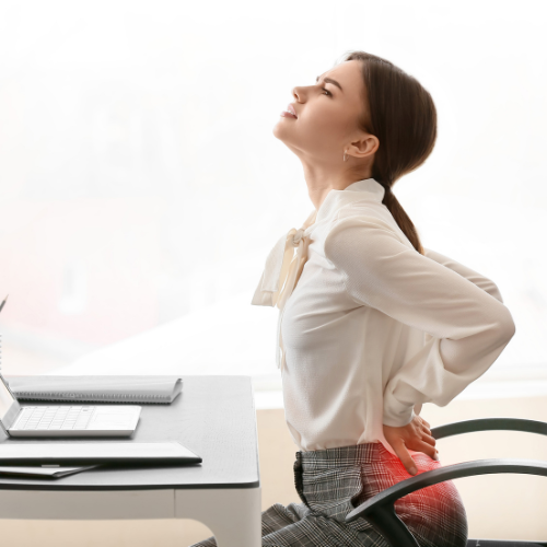 woman sitting at desk holding her back because it hurts